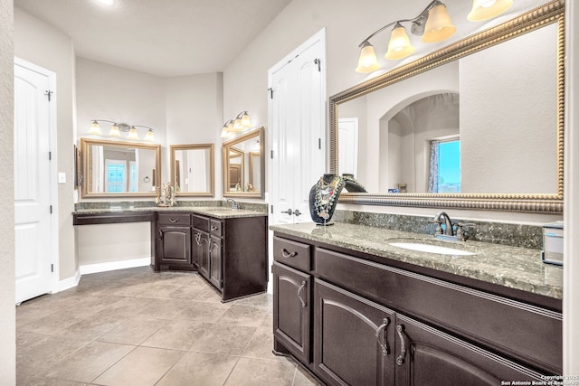 full bath featuring two vanities, tile patterned flooring, and a sink