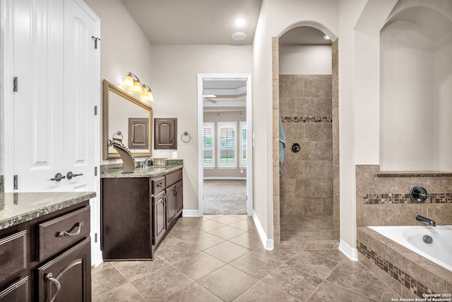 bathroom featuring tile patterned floors, a walk in shower, vanity, baseboards, and a garden tub