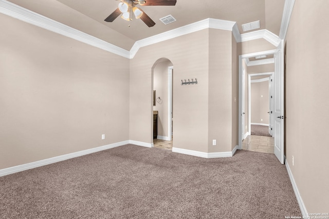 carpeted empty room featuring ceiling fan, visible vents, baseboards, ornamental molding, and arched walkways