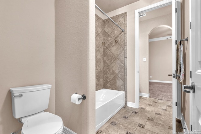 full bath with stone finish floor, toilet, shower / bathtub combination, baseboards, and visible vents