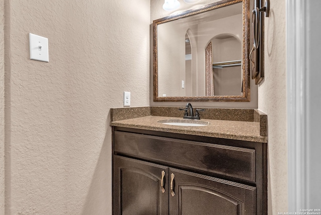 bathroom featuring a textured wall and vanity