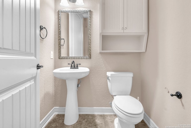 bathroom with toilet, a sink, tile patterned floors, and baseboards