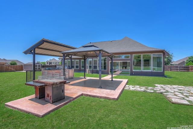 rear view of property featuring a gazebo, a patio area, a yard, and a fenced backyard