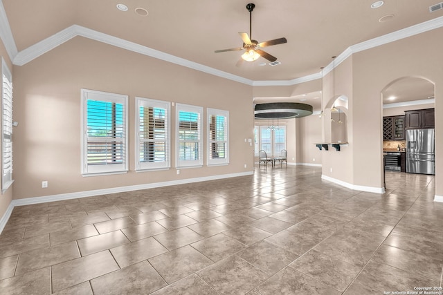 unfurnished living room featuring light tile patterned floors, ceiling fan, baseboards, ornamental molding, and arched walkways