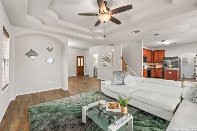 living area featuring a tray ceiling, a ceiling fan, wood finished floors, and visible vents