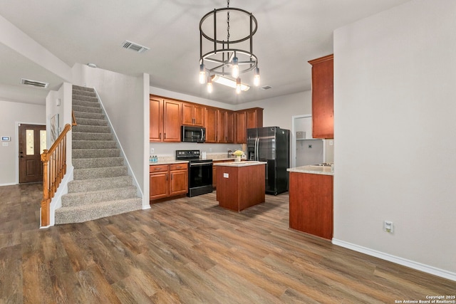 kitchen with light countertops, a kitchen island, black appliances, and visible vents