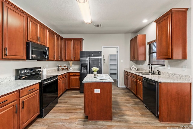 kitchen with visible vents, a sink, black appliances, and light wood-type flooring