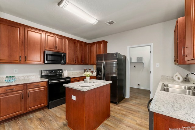 kitchen featuring a sink, black electric range, stainless steel microwave, refrigerator with ice dispenser, and visible vents