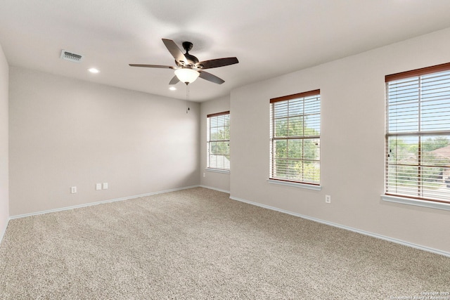 carpeted spare room with baseboards, plenty of natural light, ceiling fan, and visible vents
