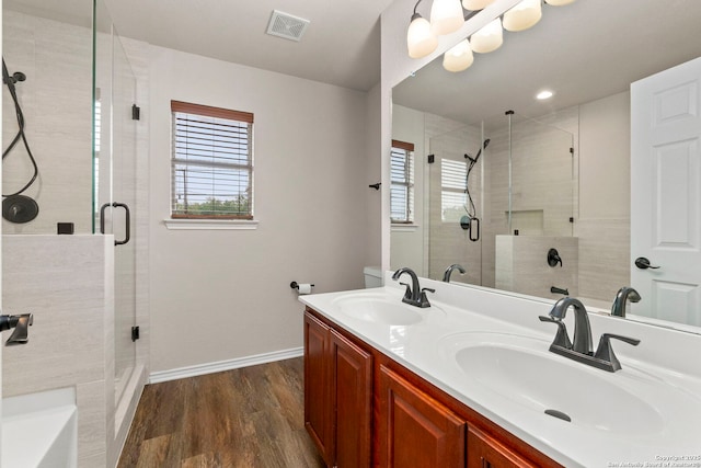 full bathroom featuring visible vents, a sink, wood finished floors, and a stall shower