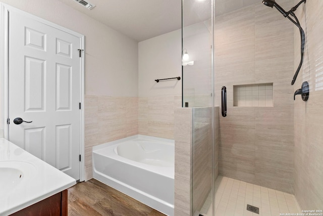full bath featuring a garden tub, visible vents, a shower stall, wood finished floors, and vanity