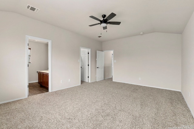 unfurnished bedroom featuring visible vents, vaulted ceiling, baseboards, ensuite bathroom, and carpet