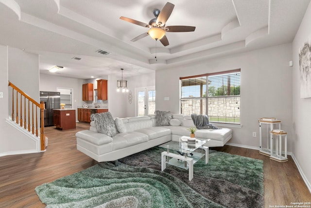living room with visible vents, a raised ceiling, ceiling fan, and dark wood finished floors