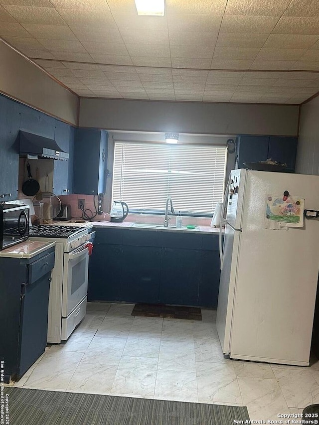 kitchen with white appliances, blue cabinetry, marble finish floor, range hood, and a sink