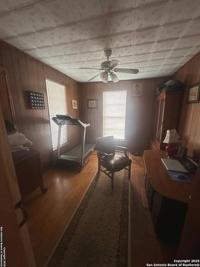 interior space with wooden walls, ceiling fan, and wood finished floors
