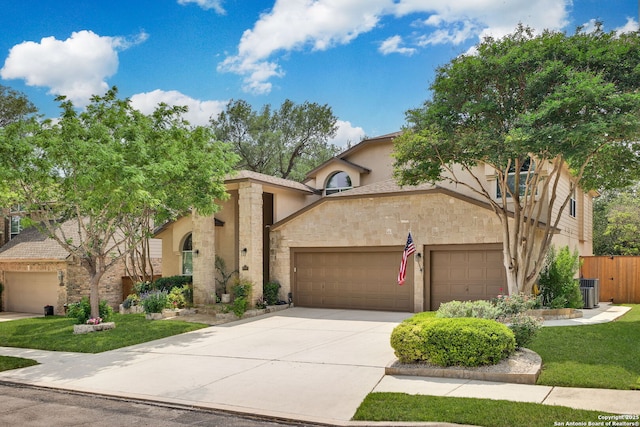mediterranean / spanish house with fence, a front yard, stone siding, an attached garage, and driveway