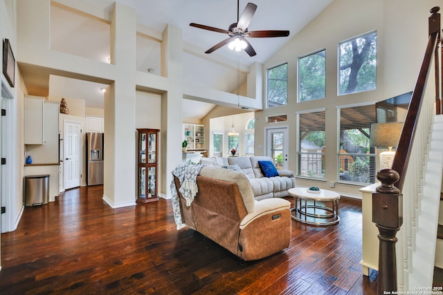 living area with baseboards, high vaulted ceiling, stairway, dark wood-type flooring, and a ceiling fan