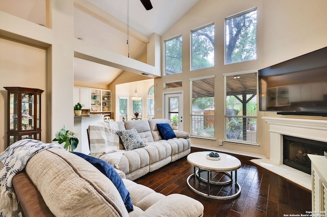 living room with high vaulted ceiling, ceiling fan, a fireplace with raised hearth, and dark wood-style floors