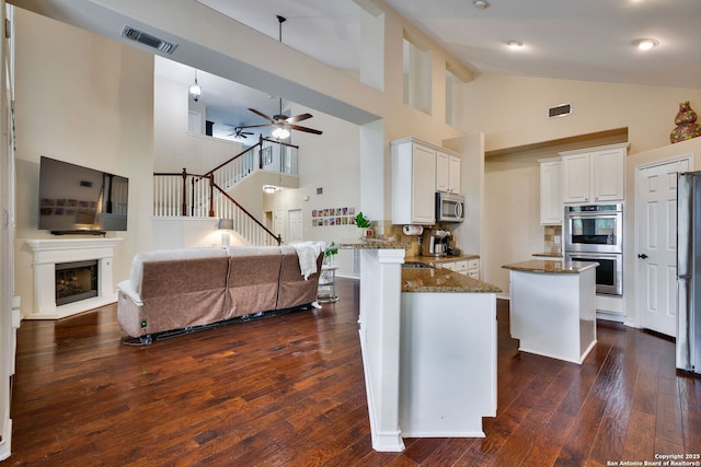kitchen featuring visible vents, dark stone counters, dark wood finished floors, and appliances with stainless steel finishes