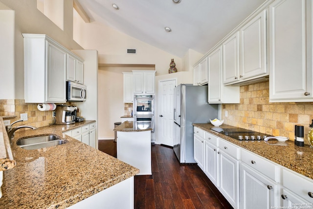kitchen featuring appliances with stainless steel finishes, a sink, stone countertops, lofted ceiling, and white cabinetry