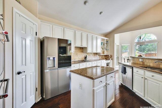 kitchen with a center island, a sink, dark stone countertops, appliances with stainless steel finishes, and backsplash