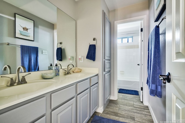 bathroom with double vanity, baseboards, a sink, and wood finished floors