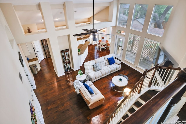living area featuring wood-type flooring, baseboards, stairs, and a high ceiling