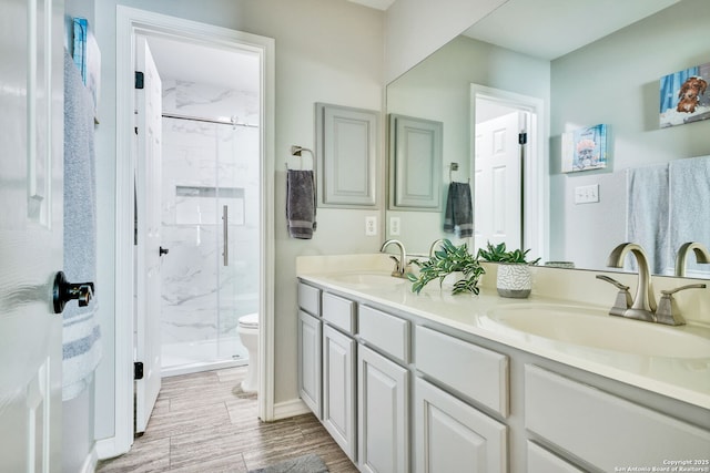 full bath featuring double vanity, a sink, a marble finish shower, and toilet