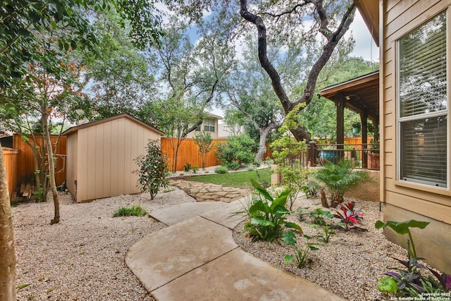view of yard with a storage unit, a fenced backyard, an outbuilding, and a patio