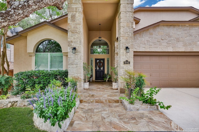 entrance to property with stucco siding, an attached garage, driveway, and stone siding