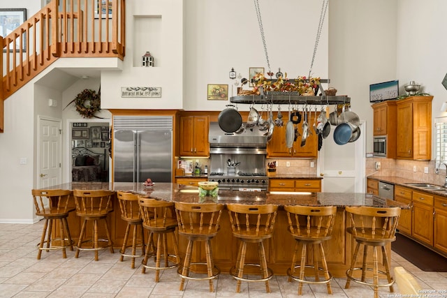 kitchen featuring built in appliances, tasteful backsplash, a sink, and a high ceiling