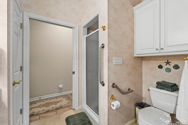 bathroom with toilet, a stall shower, and baseboards