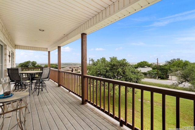 wooden terrace with outdoor dining area and a lawn