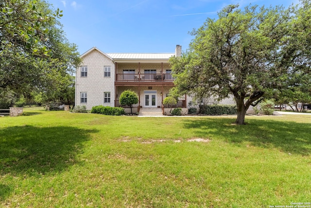 back of house with a chimney, french doors, and a yard