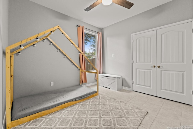 unfurnished bedroom featuring a closet, a ceiling fan, tile patterned floors, and baseboards