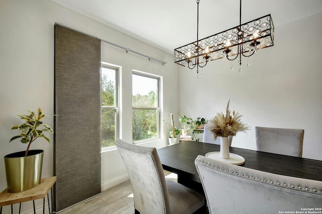 dining room featuring a chandelier, light wood finished floors, and baseboards