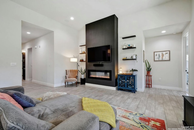 living area featuring a large fireplace, recessed lighting, light wood-style flooring, and baseboards