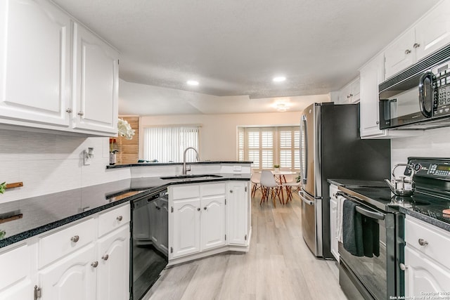 kitchen with white cabinetry, a sink, light wood-style floors, black appliances, and a peninsula
