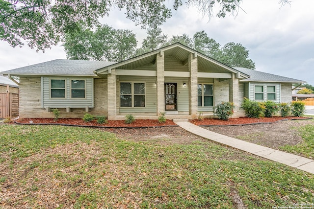 ranch-style house with a front yard, a shingled roof, and brick siding