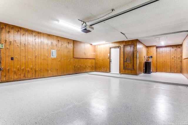 garage featuring wood walls, a garage door opener, and electric panel