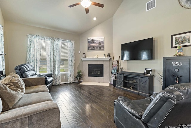 living area with visible vents, baseboards, wood-type flooring, a tile fireplace, and a ceiling fan