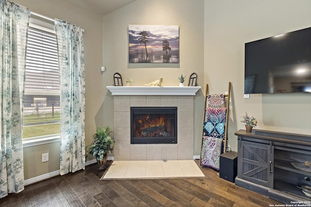 living room with a tile fireplace, a wealth of natural light, and wood finished floors