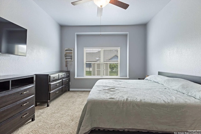 bedroom with ceiling fan, light colored carpet, and baseboards