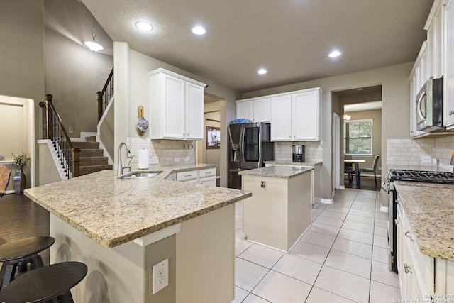 kitchen with tasteful backsplash, a peninsula, appliances with stainless steel finishes, and a sink