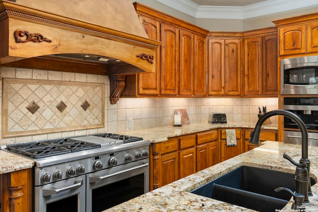 kitchen with appliances with stainless steel finishes, light stone counters, custom range hood, and a sink