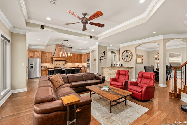 living area with crown molding, ceiling fan, visible vents, arched walkways, and wood finished floors