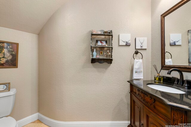 half bath featuring toilet, vaulted ceiling, and vanity