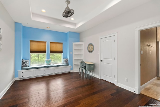 interior space featuring hardwood / wood-style floors, a tray ceiling, recessed lighting, and baseboards