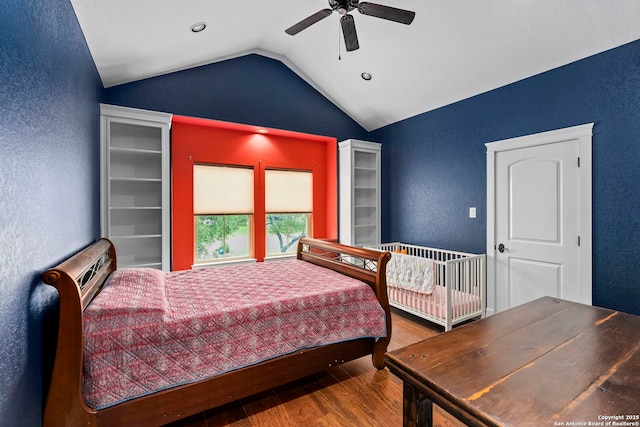 bedroom featuring lofted ceiling, a wall unit AC, ceiling fan, a textured wall, and wood finished floors