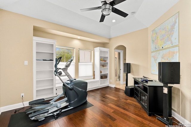 workout room featuring dark wood-type flooring, ceiling fan, baseboards, and arched walkways
